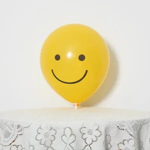 Close-up of yellow matte latex balloon with black smiley face on a white stand