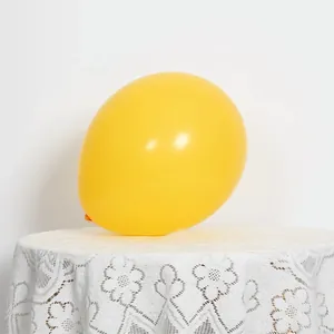 Close-up of yellow matte latex balloon on a white lace tablecloth for birthday party decor