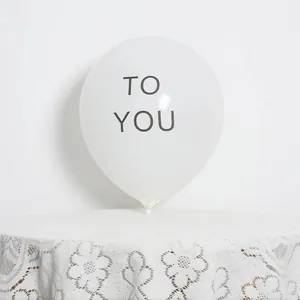 Detail of matte white 10-inch latex balloon with grey TO YOU text on lace tablecloth