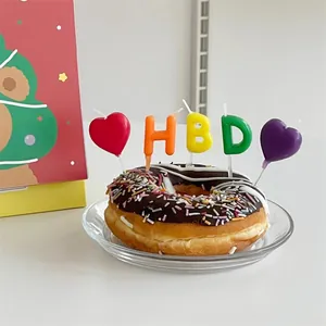 Colorful HBD letter and heart birthday candles set on top of a chocolate donut