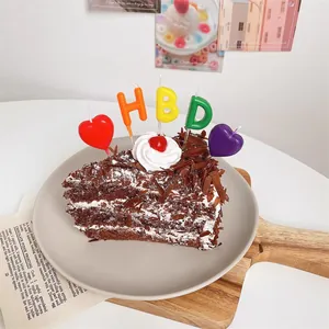 Colorful HBD letter and heart-shaped birthday cake candles set on a chocolate cake
