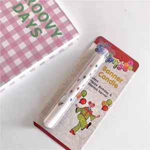Musical surprise banner birthday candle with colorful balloon patterns in blister pack