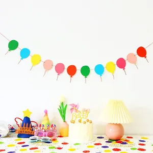 Detail of birthday party set with colorful banners, hats, and glasses in warm indoor setting