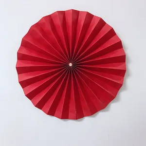 Detailed view of a red pleated paper fan flower with center pearl for wedding decor