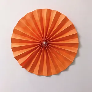 Detail of bright orange pleated paper fan flower with a central pearl for wedding decor
