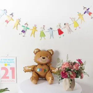 Detail of a brown teddy bear balloon with rainbow HAPPY text for birthday party decoration