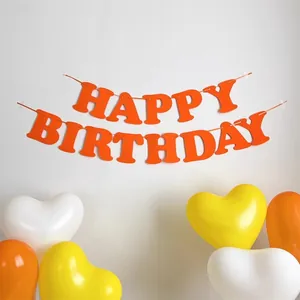 Dettaglio dello striscione arancione Happy Birthday con palloncini a cuore per decorazioni