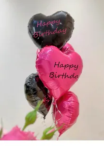 Close-up of black and magenta heart-shaped foil balloons with Happy Birthday print