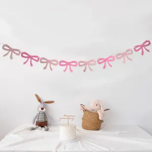 Pink felt bow garland hanging above a birthday cake with a soft plush rabbit toy decoration