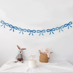 Detail of blue felt bow garland hanging on a white wall for birthday party decor