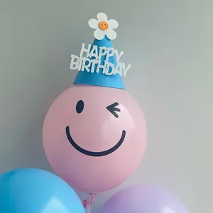Detail van roze knipoog smiley ballon met blauwe Happy Birthday feesthoed decor