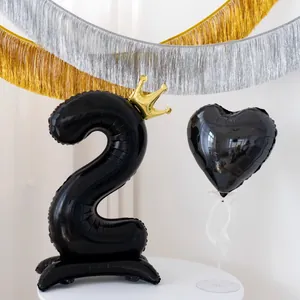 Detalle de globo negro número 2 con corona dorada y base de corazón para cumpleaños