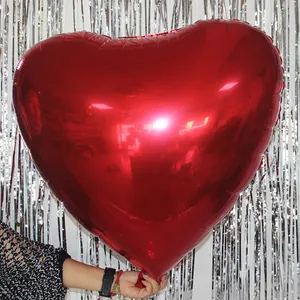 Detailed view of large red heart-shaped foil balloon with metallic finish and silver backdrop