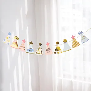 Banderole d'anniversaire pastel avec motifs dorés suspendue sur un mur blanc