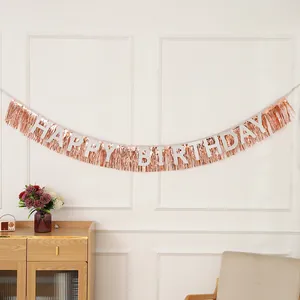 Rideau à franges or rose et bannière Happy Birthday blanche sur un mur blanc