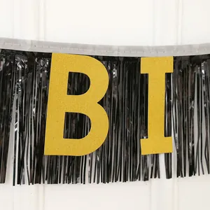 Détail de lettres dorées pailletées sur rideau de franges noires pour décoration