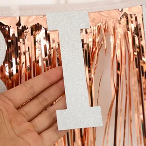 Détail d'une lettre à paillettes argentées et rideau à franges rose doré pour fête