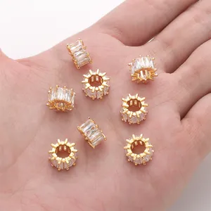 Makroaufnahme von acht 18K vergoldeten Rad-Anhängern mit Zirkonia-Steinen in der Hand