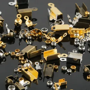 Sortierte Schmuckzubehörteile in Gold und Silber auf reflektierender schwarzer Fläche