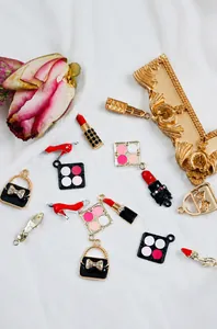 Detail van geëmailleerde bedeltjes in de vorm van lippenstift en handtas voor sieraden