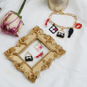 Bracciale fai-da-te con ciondoli a rossetto, tacchi alti e borsa su cornice vintage