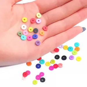 Hand hält bunte 6mm Heishi-Perlen aus Polymer-Ton für DIY-Schmuckherstellung