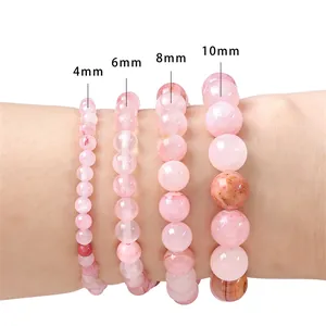 Pink synthetic quartz round bead bracelets in 4mm to 10mm sizes on model's wrist