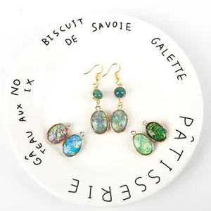 Détail des pendentifs opale en forme de goutte avec bordure en cuivre doré et pierres vertes
