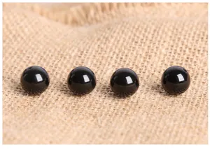 Polished black agate beads with drill holes for DIY jewelry making on linen background