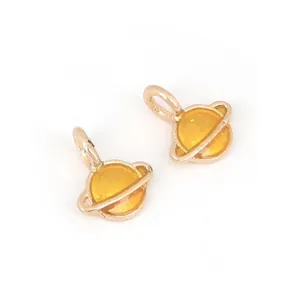 Detailaufnahme der goldenen Saturn-Anhänger mit gelber Emaille für DIY-Schmuckherstellung