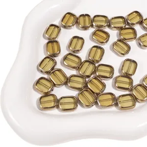 Macro shot of oval amber glass beads with gold-plated edges in a white porcelain dish
