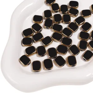 Macro detail of black rectangular glass beads with gold trim and pre-drilled holes