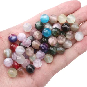 Macro detail of 10mm multi-colored cat eye resin beads held in hand for jewelry making