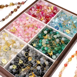 Macro view of assorted glass beads and golden alloy charms in a wooden display box