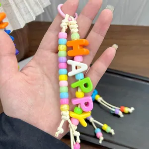 Vue macro d'un porte-clés en perles colorées fait main avec lettres blanches HAPPY