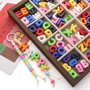 Vue macro de perles alphabet colorées en acrylique dans une boîte en bois pour bijoux DIY