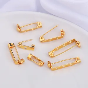 Detailed view of gold-plated safety pins with securing locks and dual-hole bases