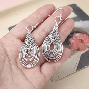 Detail of handmade silver teardrop earrings with intricate multi-layer woven wire design