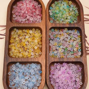 Detailed top view of 6mm acrylic flower beads in six colors displayed in a wooden tray