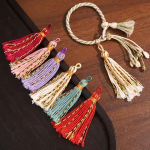 Handmade Tibetan colorful tassel pendants with braided cord bracelets on wooden tray