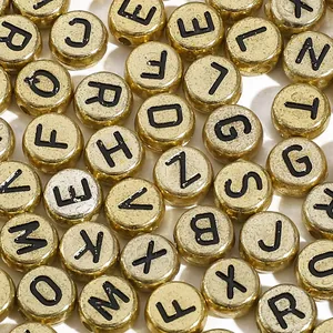 Macro detail of 4x7mm gold acrylic letter beads with black initials for DIY jewelry making