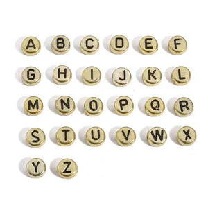 Macro detail of 4x7mm gold acrylic flat round beads with black capital letters A-Z