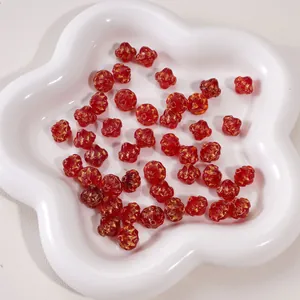 Macro shot of dark red glass four-leaf clover beads with gold accents in a white tray