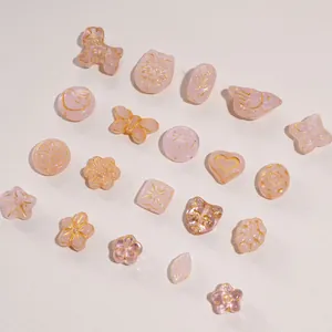 Detailed flat lay of pink glass butterfly and floral beads with gold-rimmed detailing