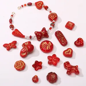 Macro view of red glass beads in heart and flower shapes with gold-painted detailing