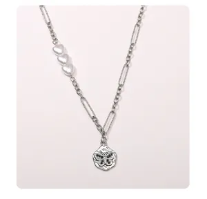 Detail of stainless steel necklace with white heart pearls and engraved butterfly pendant