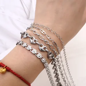 Set of stacked silver stainless steel chain bracelets with heart charms on white shirt cuff