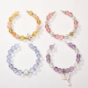 Détail de bracelets en perles de verre avec pendentifs papillon et fleurs délicats