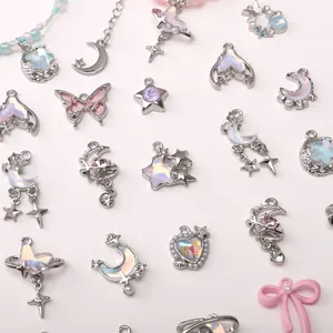 Macro detail of silver alloy charms featuring moon, butterfly, and opal resin inlays