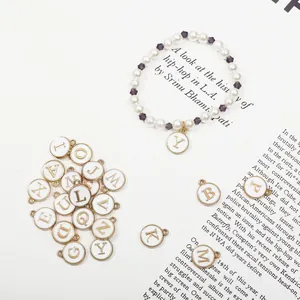 Détail de breloques alphabet en émail blanc doré avec perles et bracelet perles mauves
